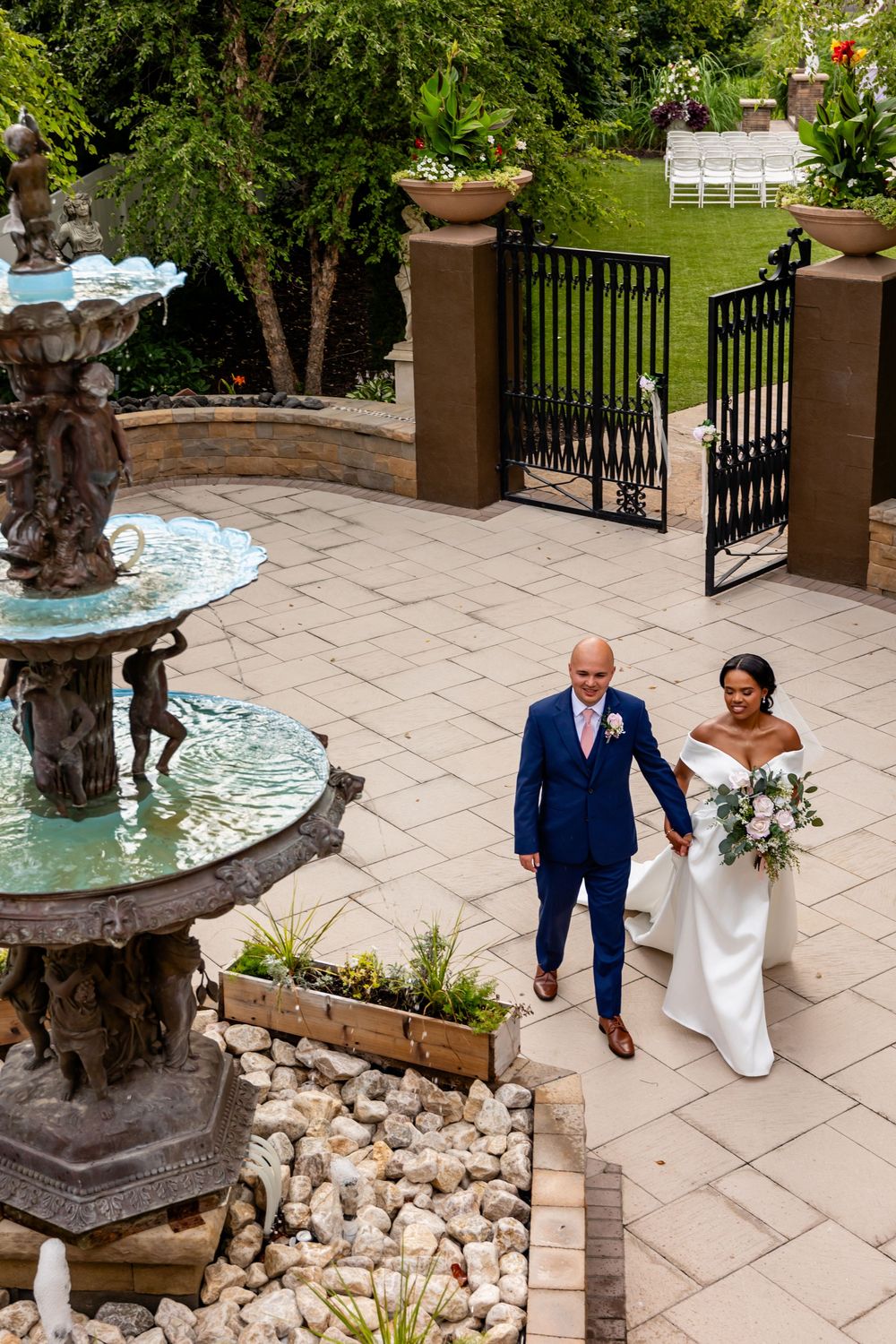 Garden wedding venue with decorative stone fountain and paved walkway.