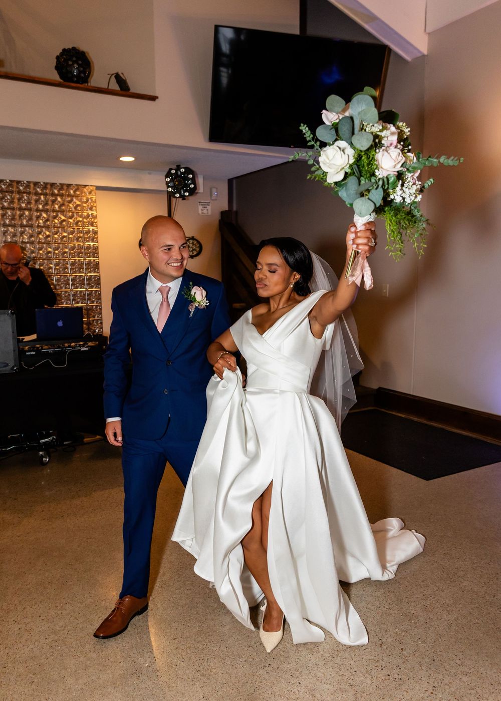 Wedding couple dancing together in an elegant reception hall with mood lighting.