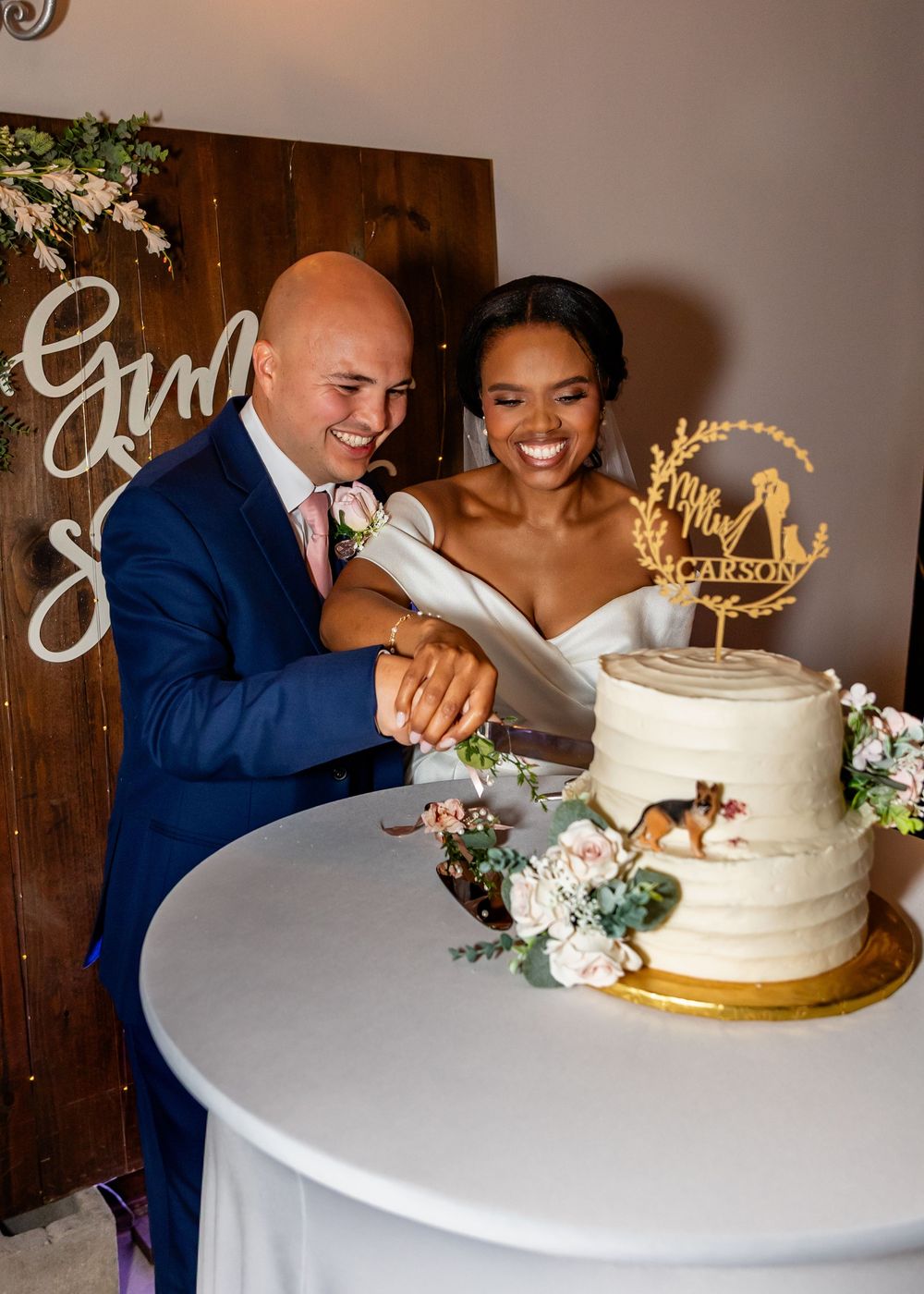 Wedding couple cutting their white and gold wedding cake at reception.