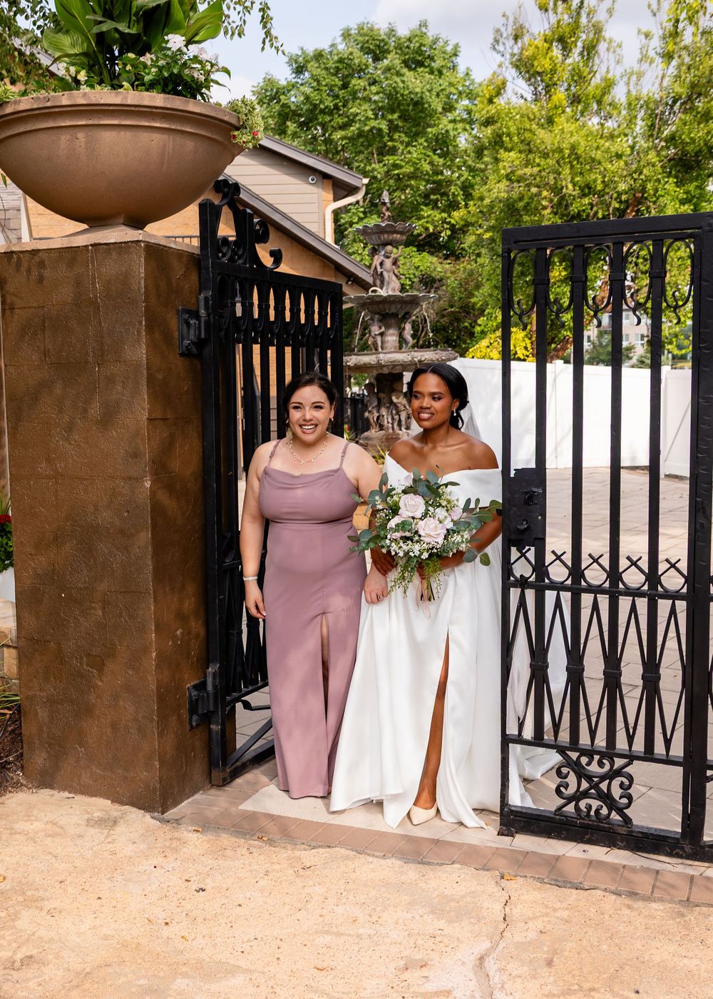 Wedding party members gather near an ornate metal gate entrance.