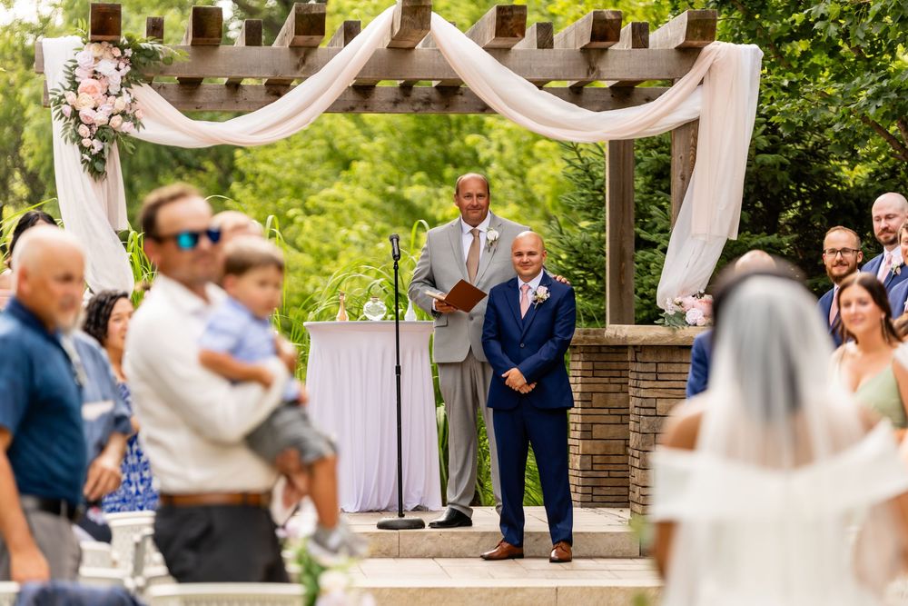 Wedding ceremony moments captured under white draped arch in garden setting.