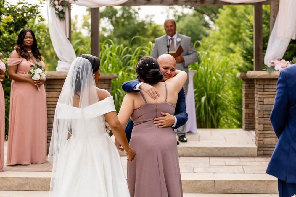 Emotional wedding ceremony moments with bridesmaids in mauve dresses looking on.