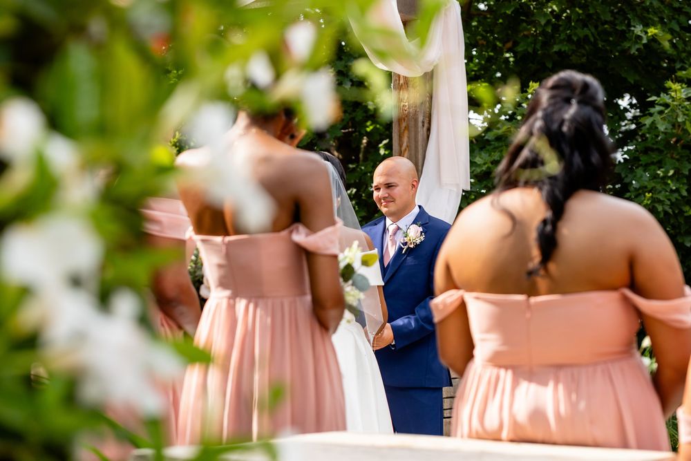 Bridesmaids in peach-colored dresses attend outdoor garden wedding ceremony.