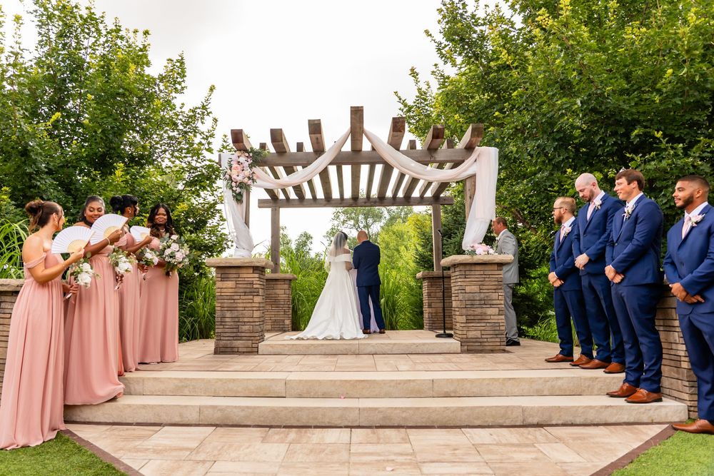 Wedding ceremony setup with elegant stone pergola and white chairs arranged outdoors at Villa Aletta in Omaha, NE.