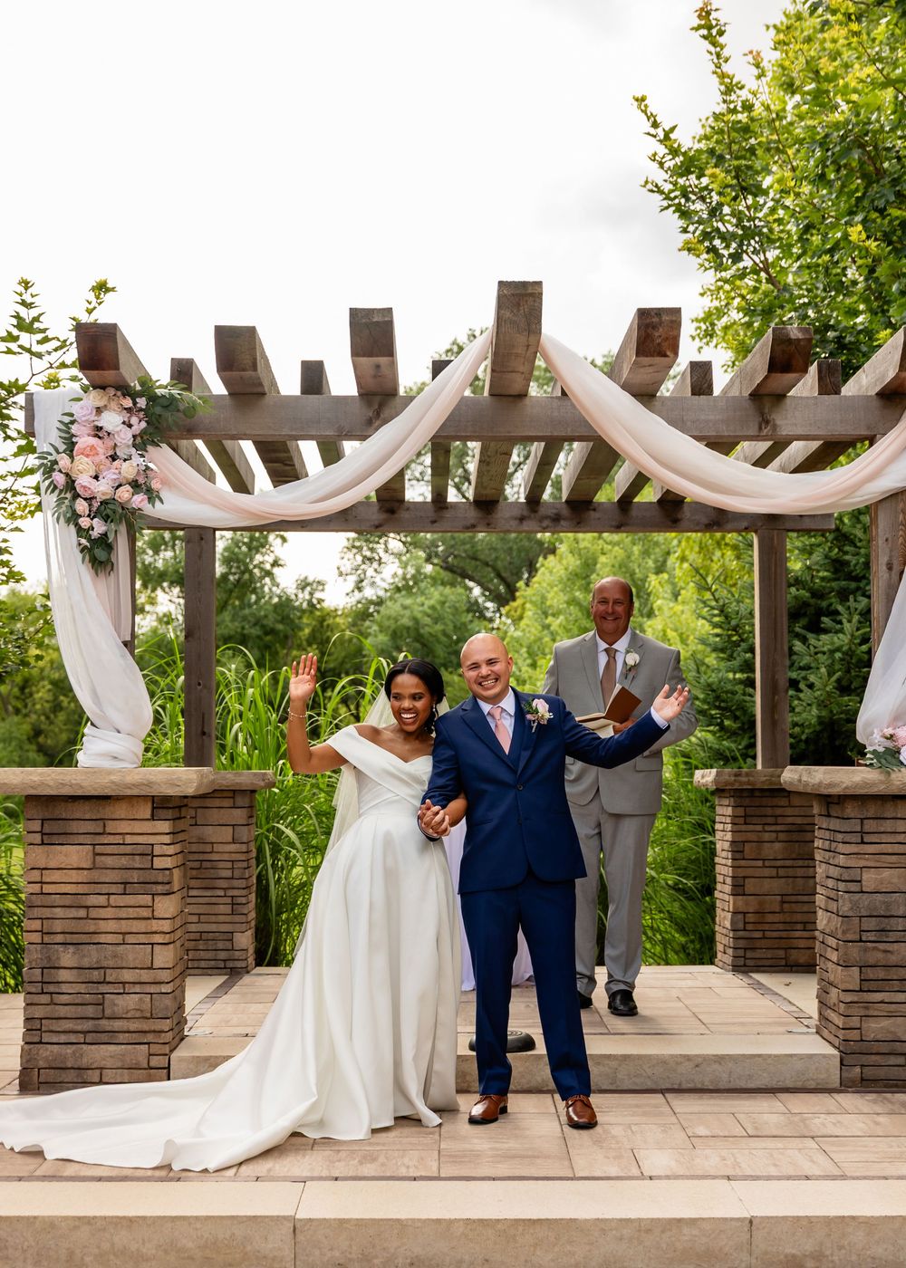Wedding ceremony moments captured under elegant stone and wood pergola with white draping at Villa Aletta in Omaha, NE.