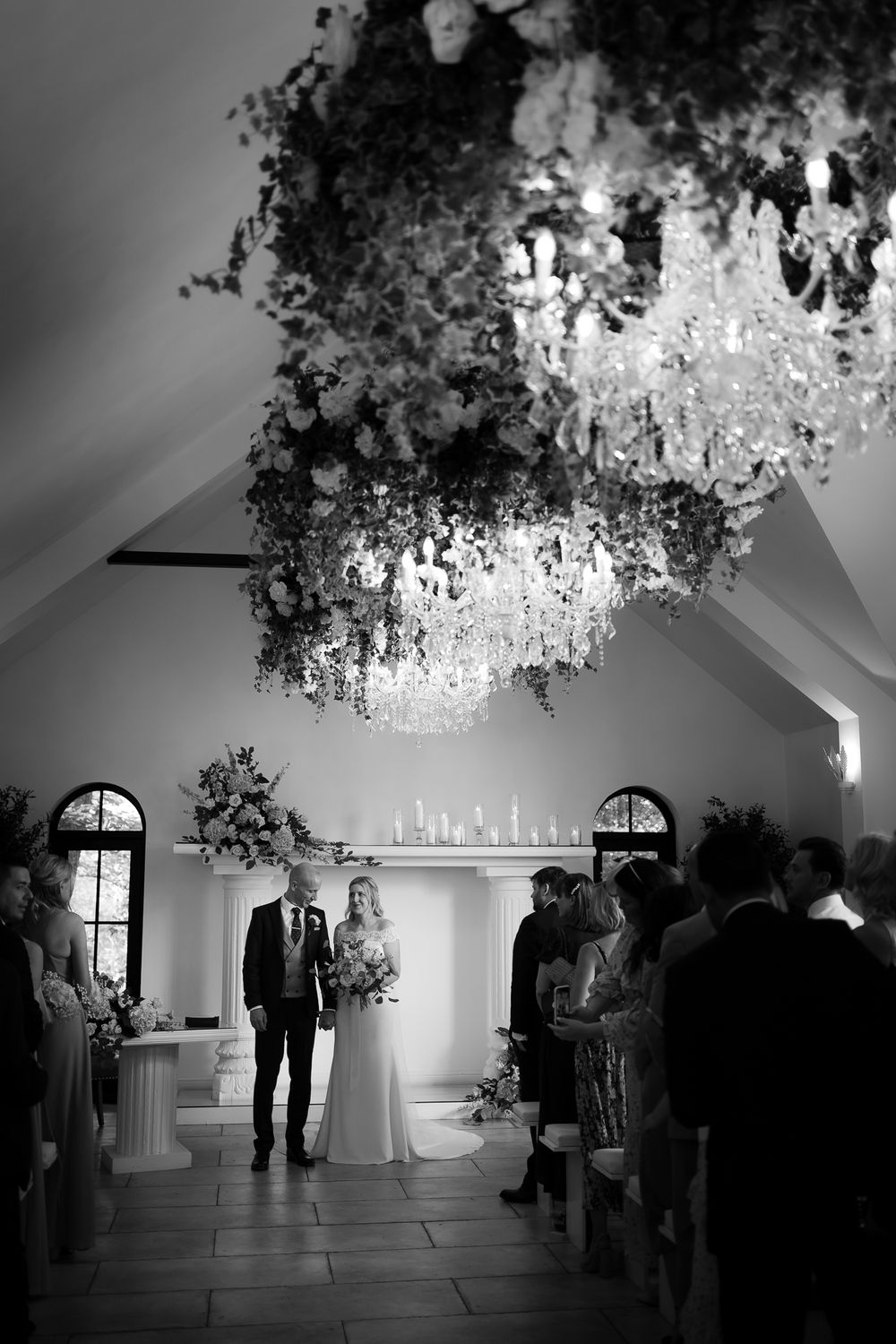 Black and white wedding photo showing dramatic chandelier and chapel interior. Woodhill Hall.