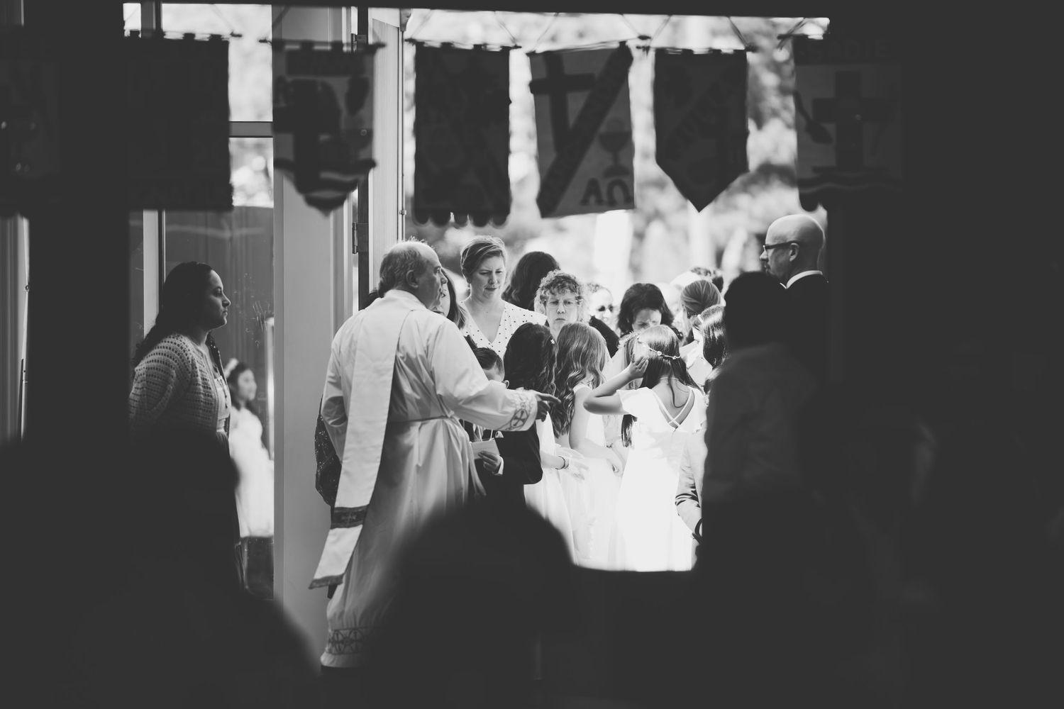A bride and groom sit together in wooden church pews during their wedding ceremony.