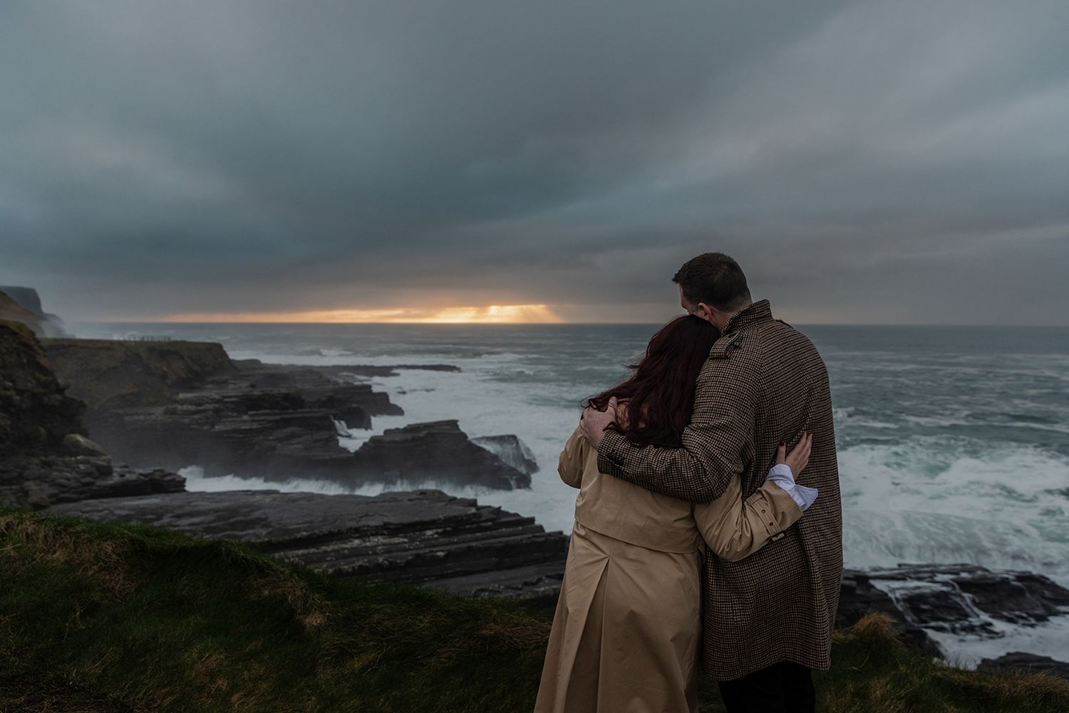 Adventure-loving couple celebrating love during cinematic stormy sunset portraits at Cliffs of Moher
