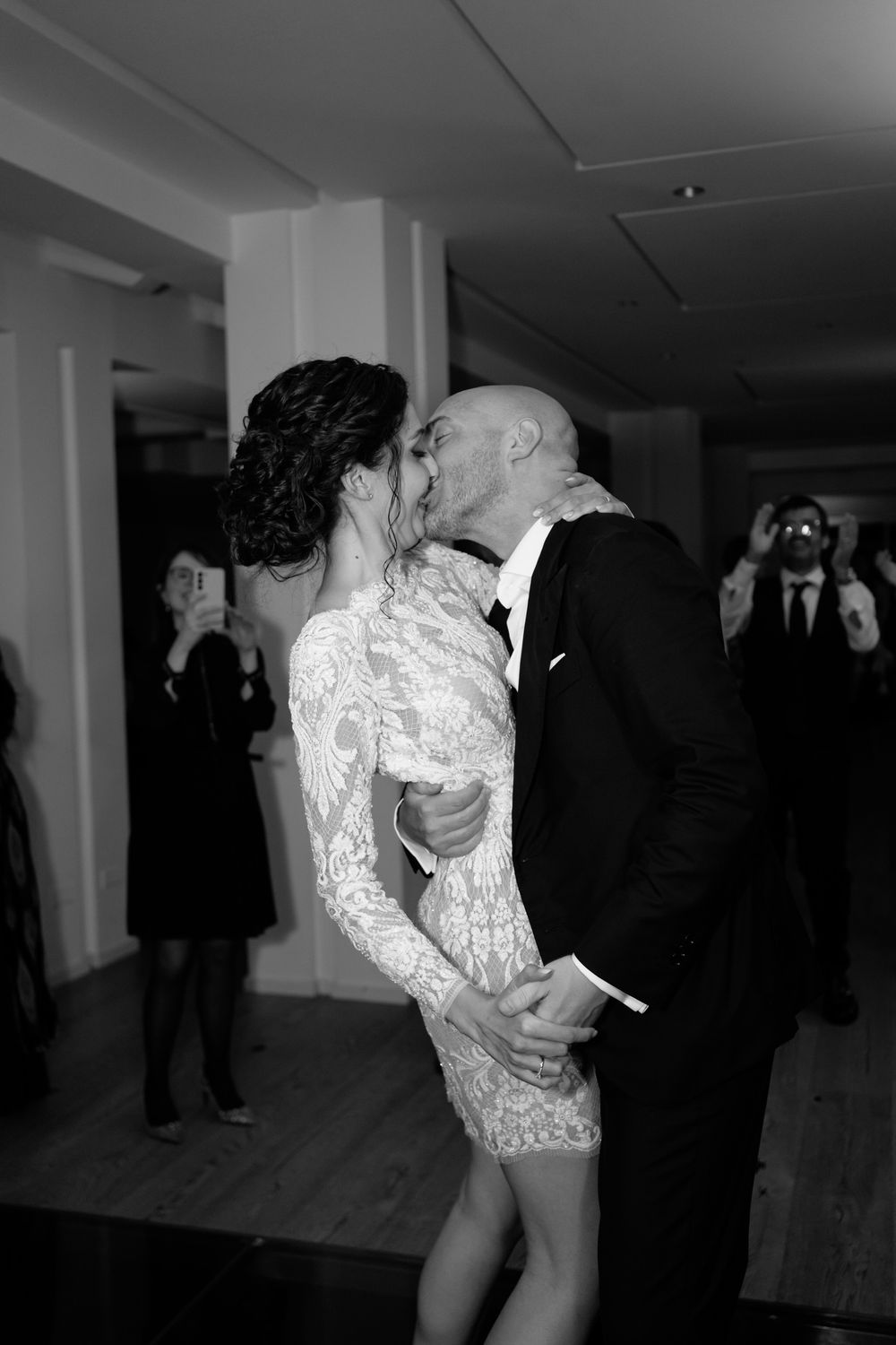 A couple in formal attire share an intimate dance dip on the dance floor at an indoor event.