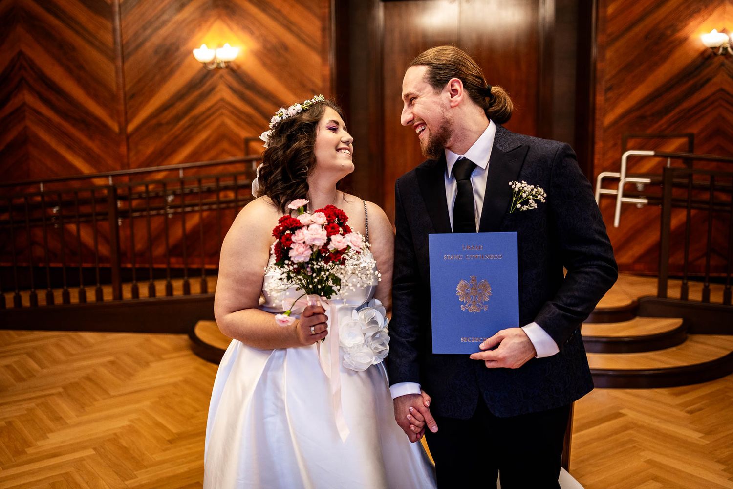 Wedding couple shares intimate moment in warmly lit wooden interior venue.