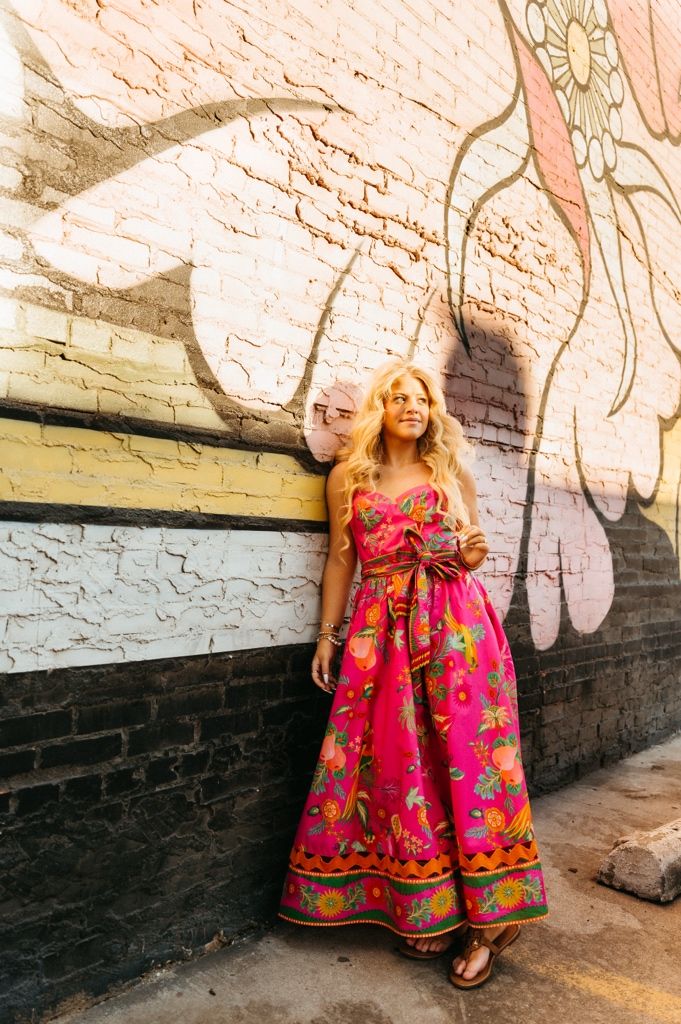 A sequence of photos showing a person in a bright pink floral dress sitting against a textured stone wall.