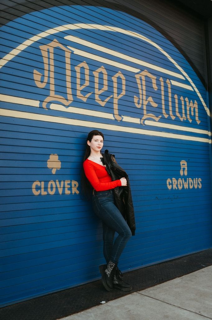 A person in a red top poses against a bright blue wall with gold lettering in a sequence of artistic urban photos.
