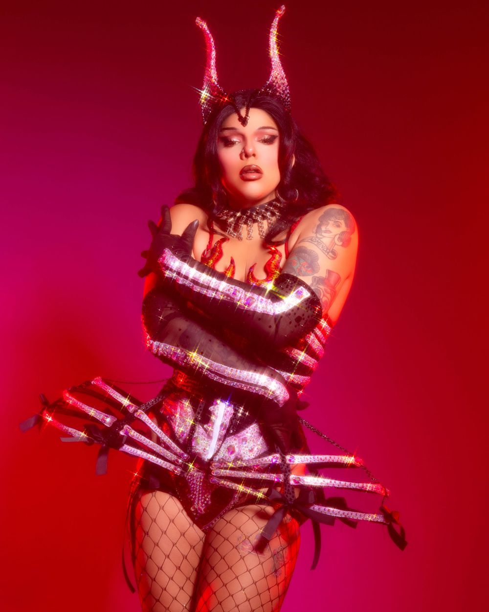 Artistic performance shot in red lighting showing a dramatic pose with glowing LED tubes against a dark background.