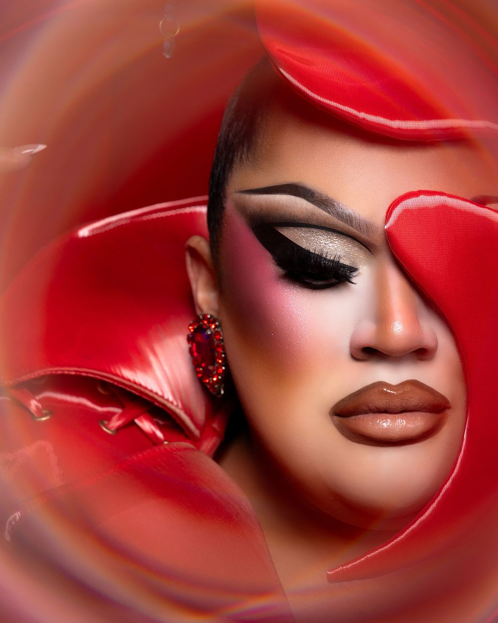 Close up beauty portrait with dramatic red lighting and glossy brown lips against dark background.