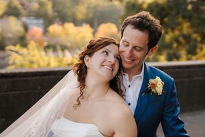 Joyful wedding couple embraces during sunset photo session in outdoor garden setting.
