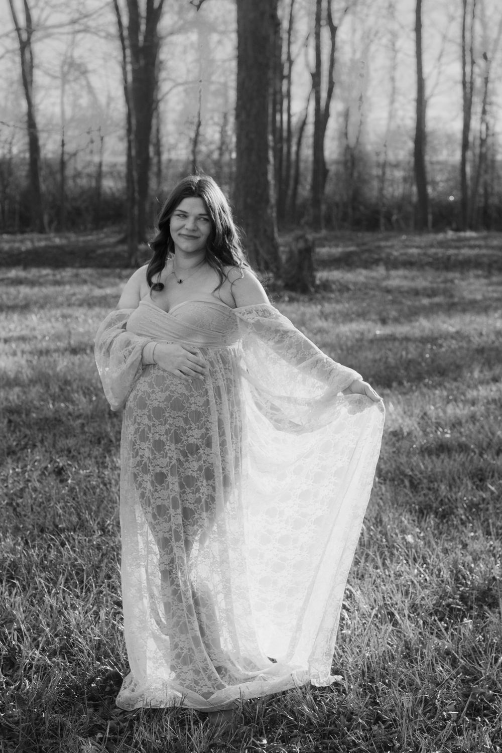 Black and White photo of a pregnant woman wearing a romantic lace dress