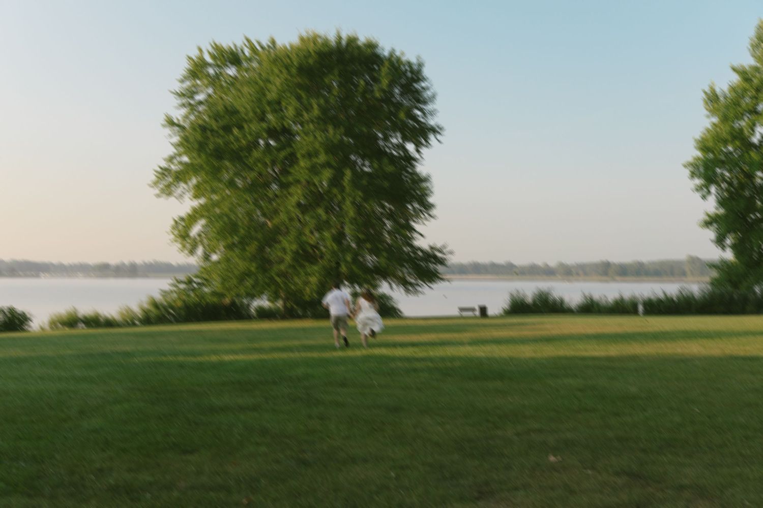 A newly engaged couple running on a hill at Stony Creek Metropark in Michigan taken by Richelle Healy Photo.