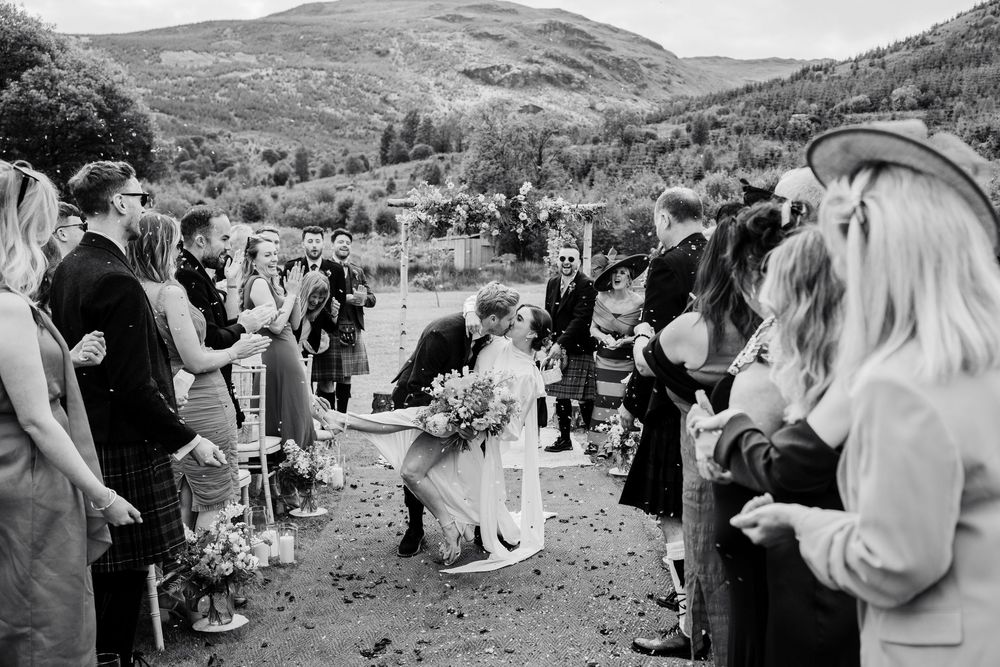 Wedding guests gather outdoors in a scenic mountain valley for a celebration.