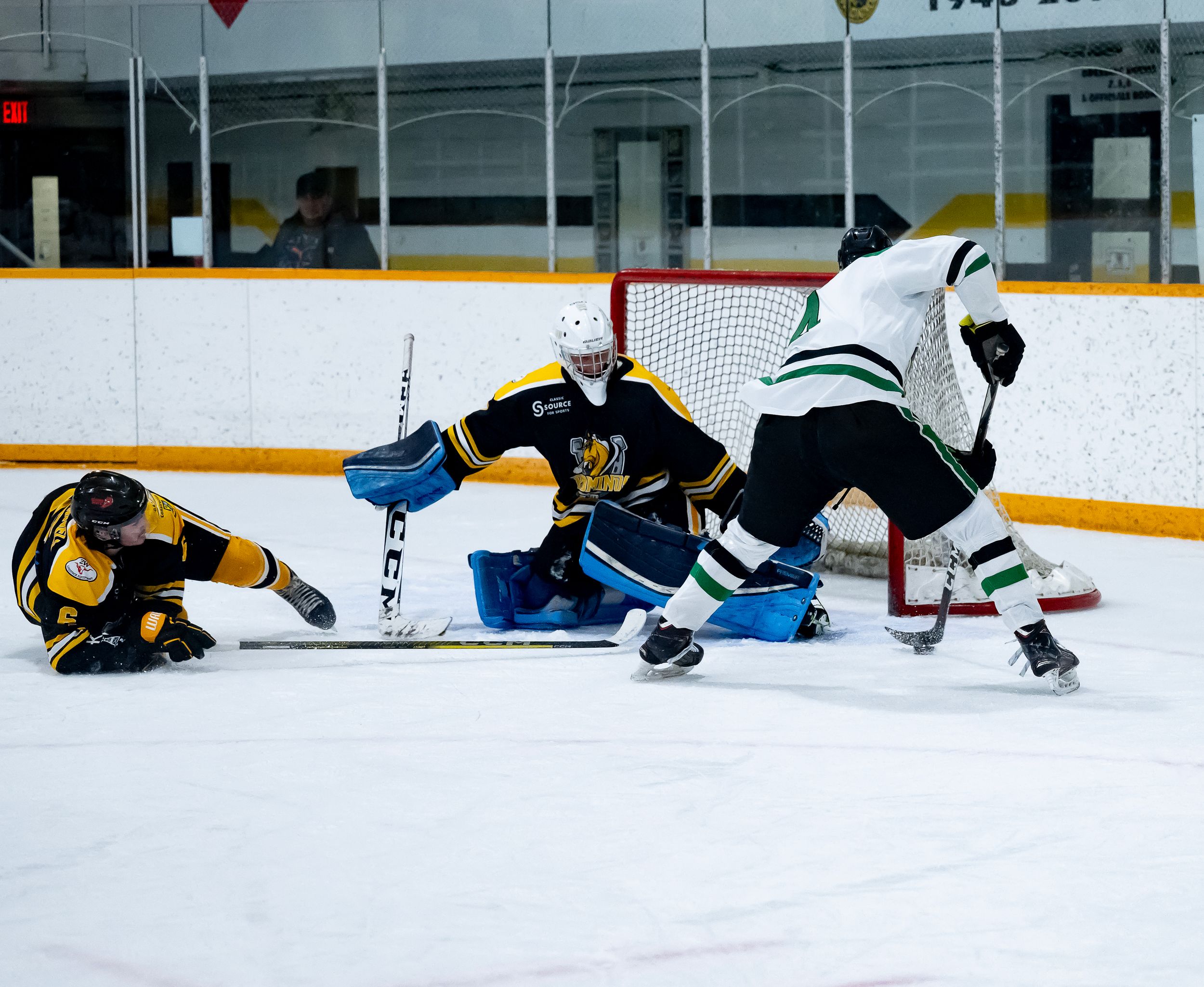 Hockey players stretch on the ice during a practice session at an indoor rink.
