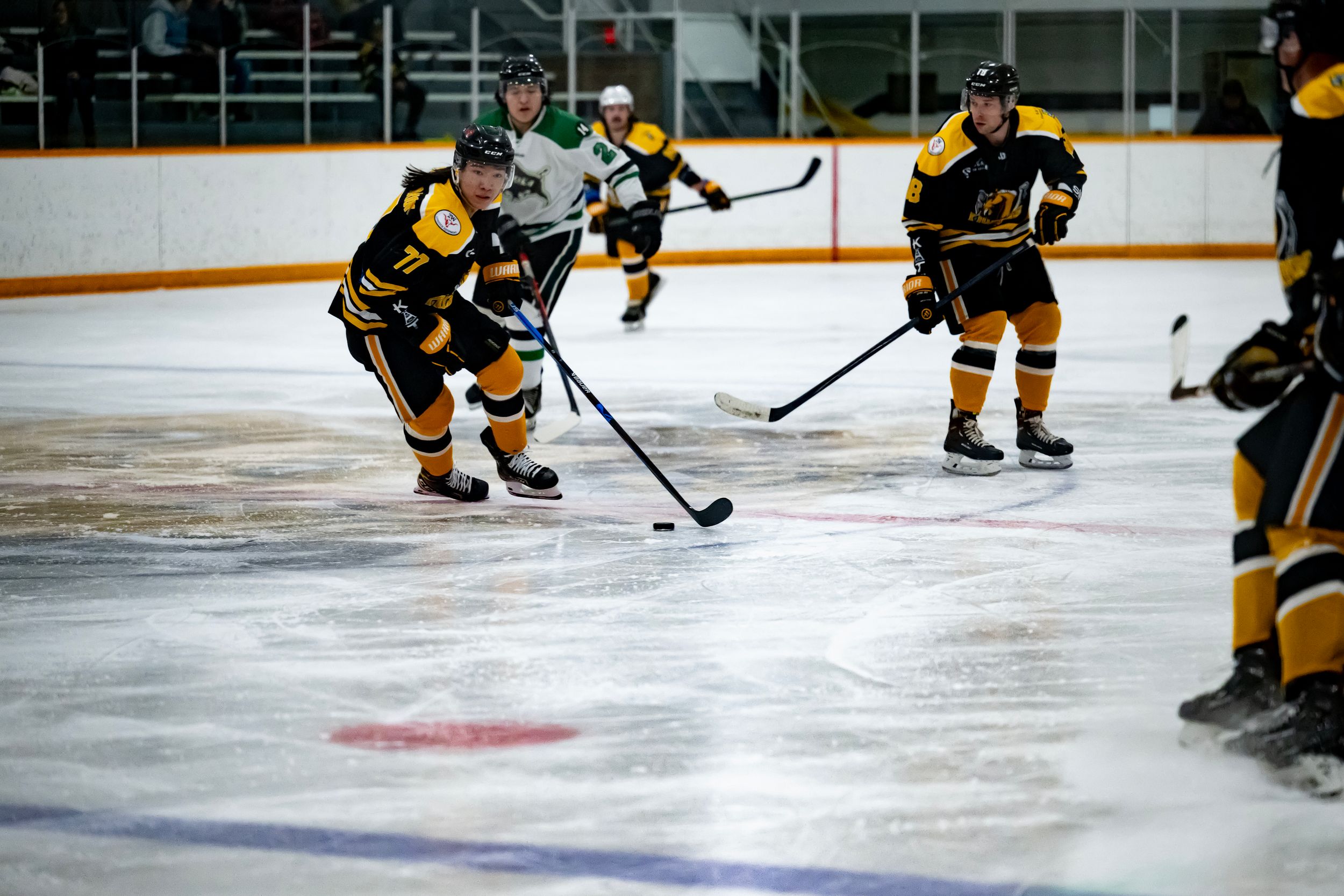 Hockey players in yellow and black uniforms skate on ice during a game sequence.