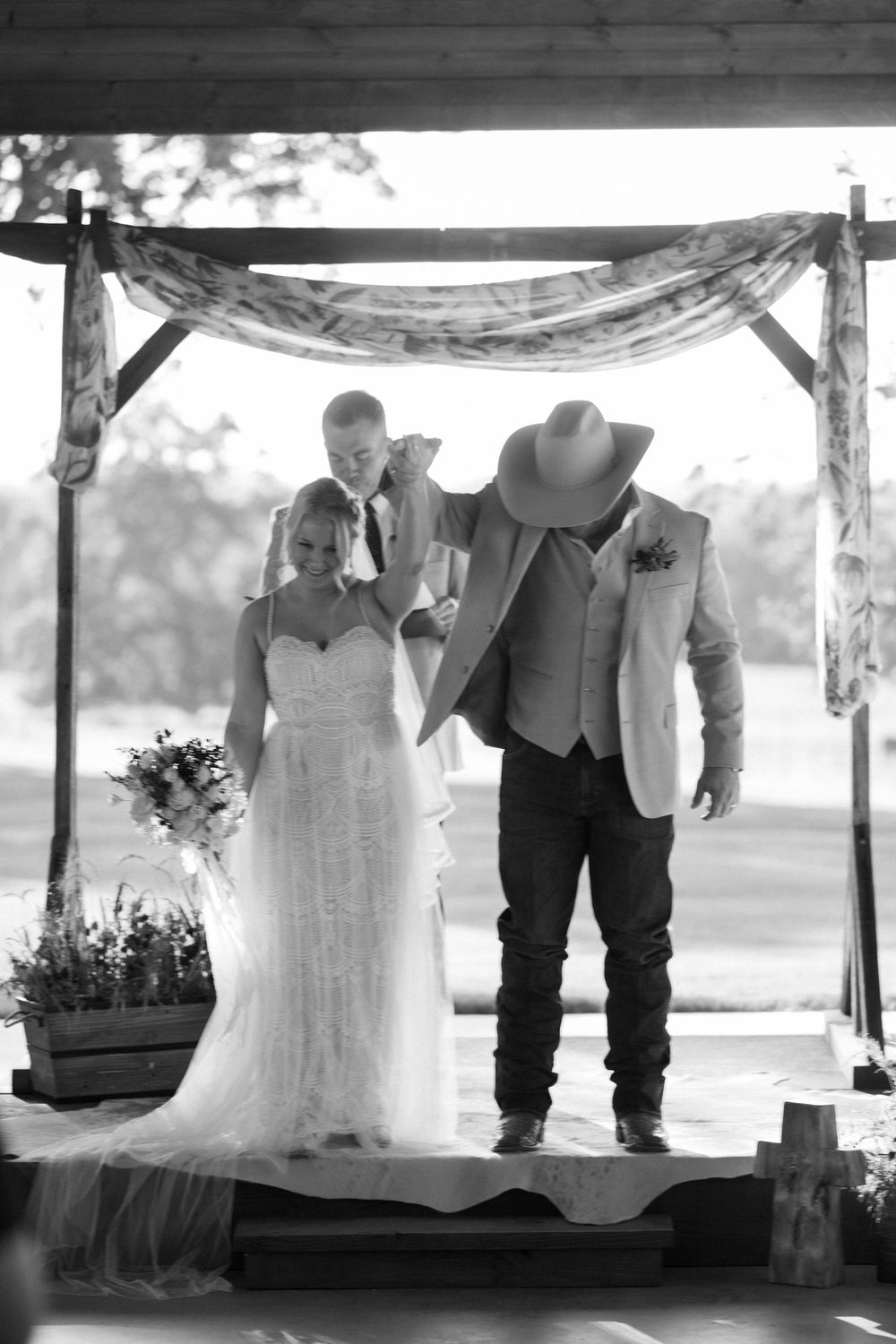 Black and white wedding ceremony photos showing couple and attendants under a rustic outdoor pavilion.