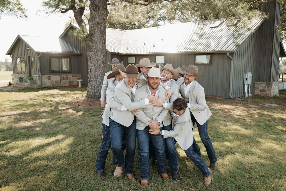 Family members in coordinating blue jeans and white tops pose playfully on a sunny lawn.