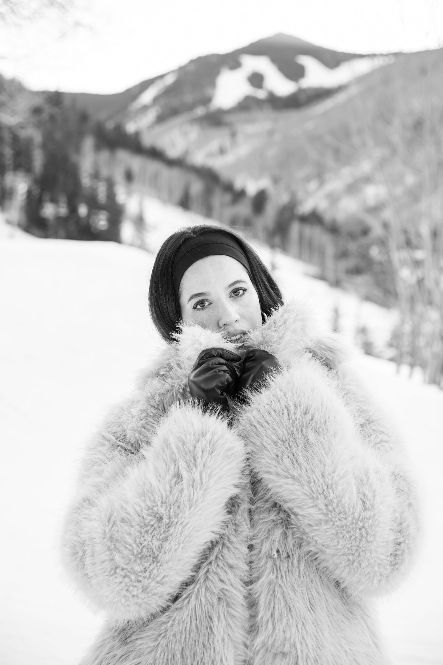 Winter fashion maternity photo shoot on a snowy bridge with mountains and aspen trees in the background in Vail Colorado
