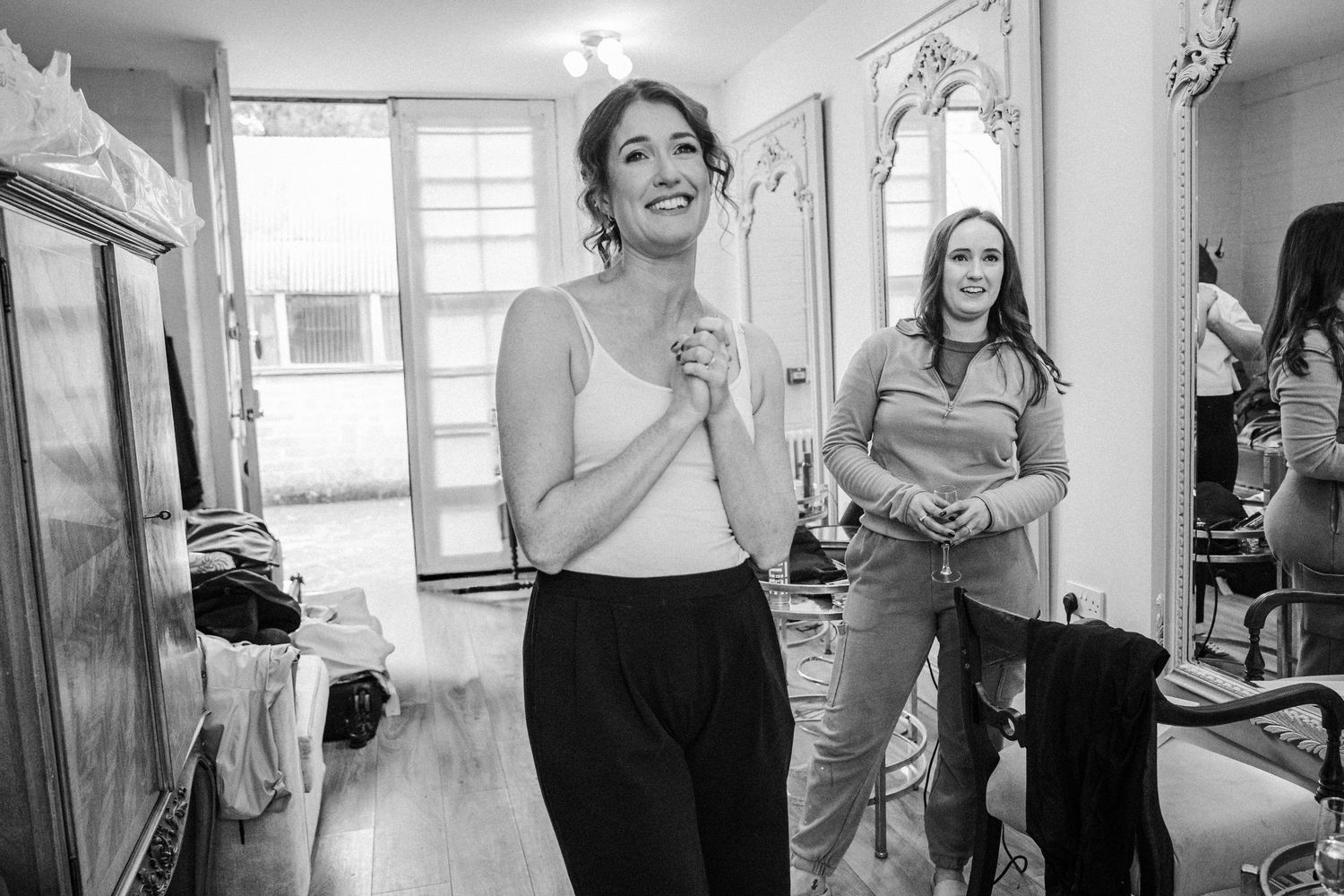 A series of black and white wedding preparation photos showing candid moments of getting ready in a bright room.