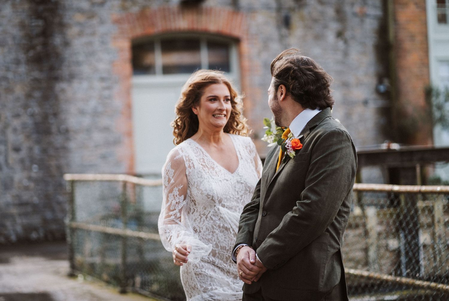 A couple shares a romantic moment together in front of a stone building on their wedding day.