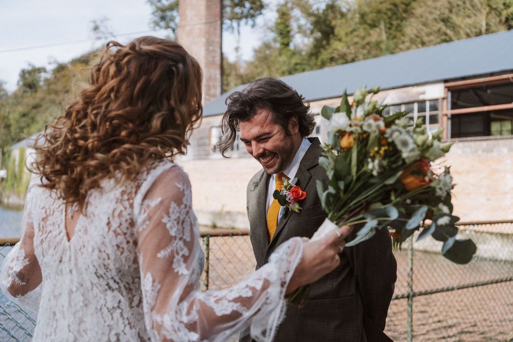 A romantic outdoor wedding ceremony with a couple exchanging vows under a rustic wooden arch in a natural setting.