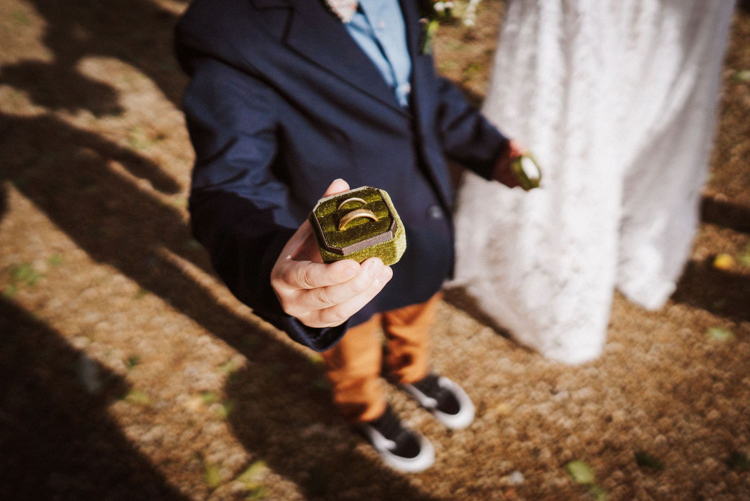 Wedding couple's feet and legs stand together on rustic ground during outdoor ceremony.