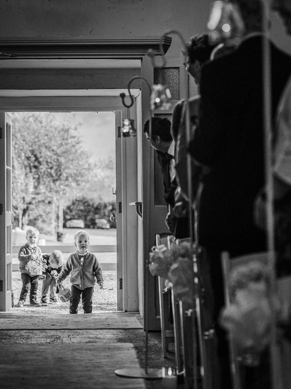 A silhouetted figure walks past a bright doorway in a dark hallway creating a dramatic contrast in black and white.