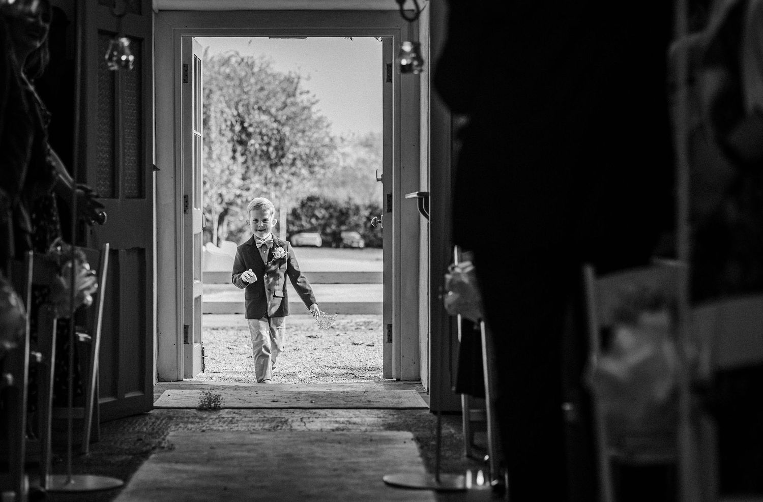 A silhouetted figure walks through a doorway or archway in black and white photography.