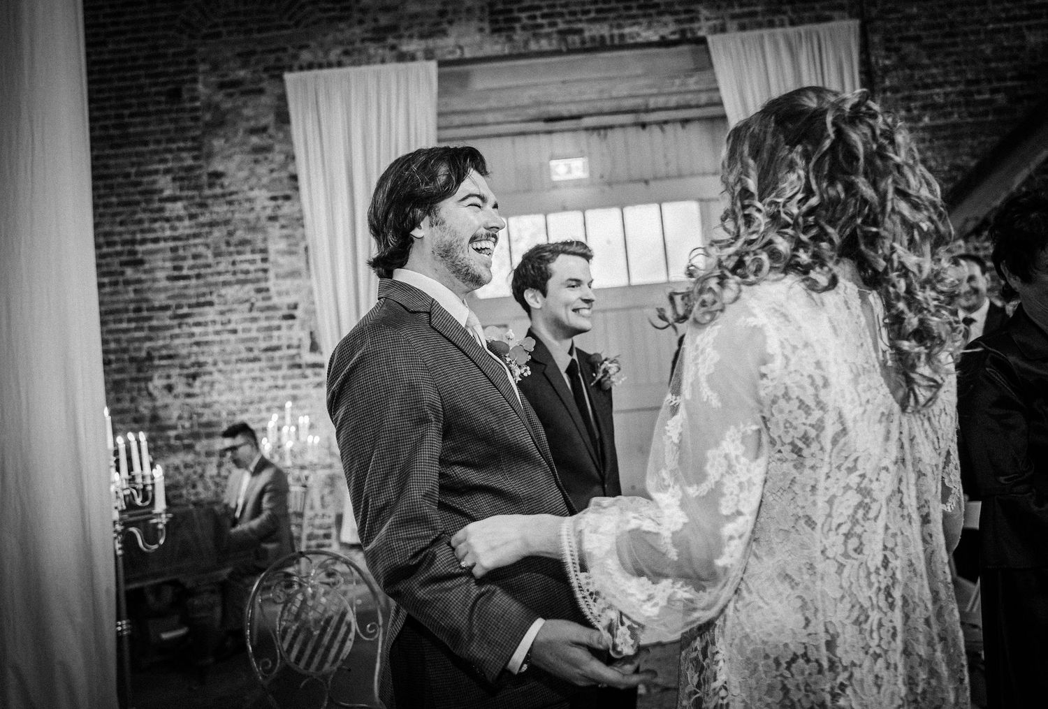 A joyful wedding celebration moment captured in black and white at a rustic brick venue.
