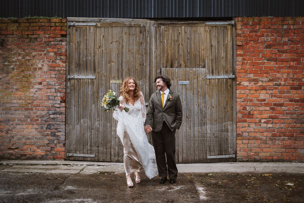 A couple poses together against rustic brick and wooden backdrops in a series of romantic wedding photos.