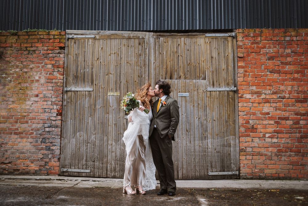 Rustic wooden doors with weathered textures line up against a vintage red brick wall creating an industrial aesthetic.