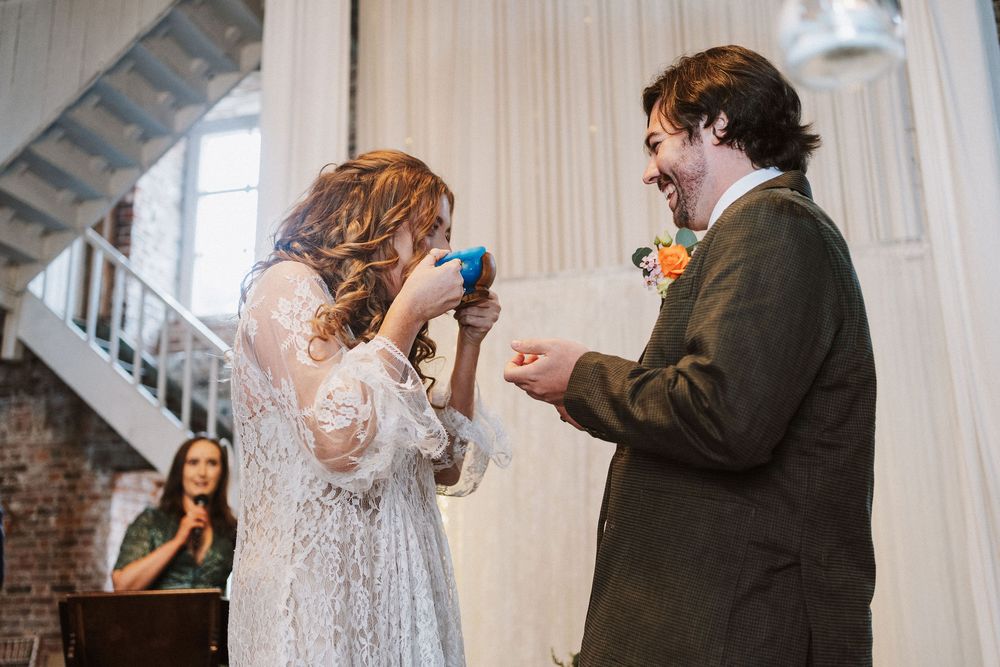 A couple shares a tender moment during their wedding ceremony in a rustic industrial venue.