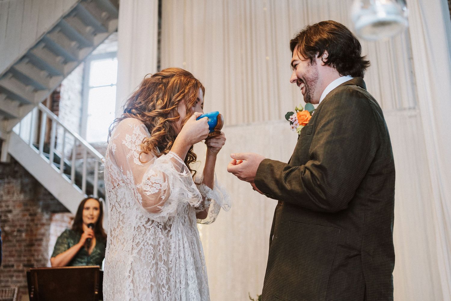A couple shares a tender moment during their wedding ceremony in a rustic industrial venue.