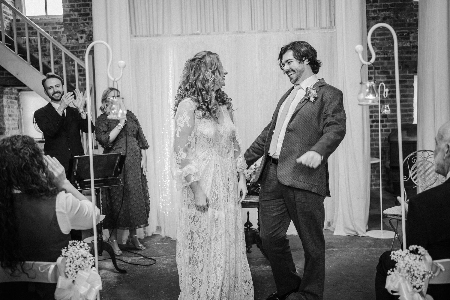 A collection of black and white wedding photos showing candid moments between couples during their celebration.