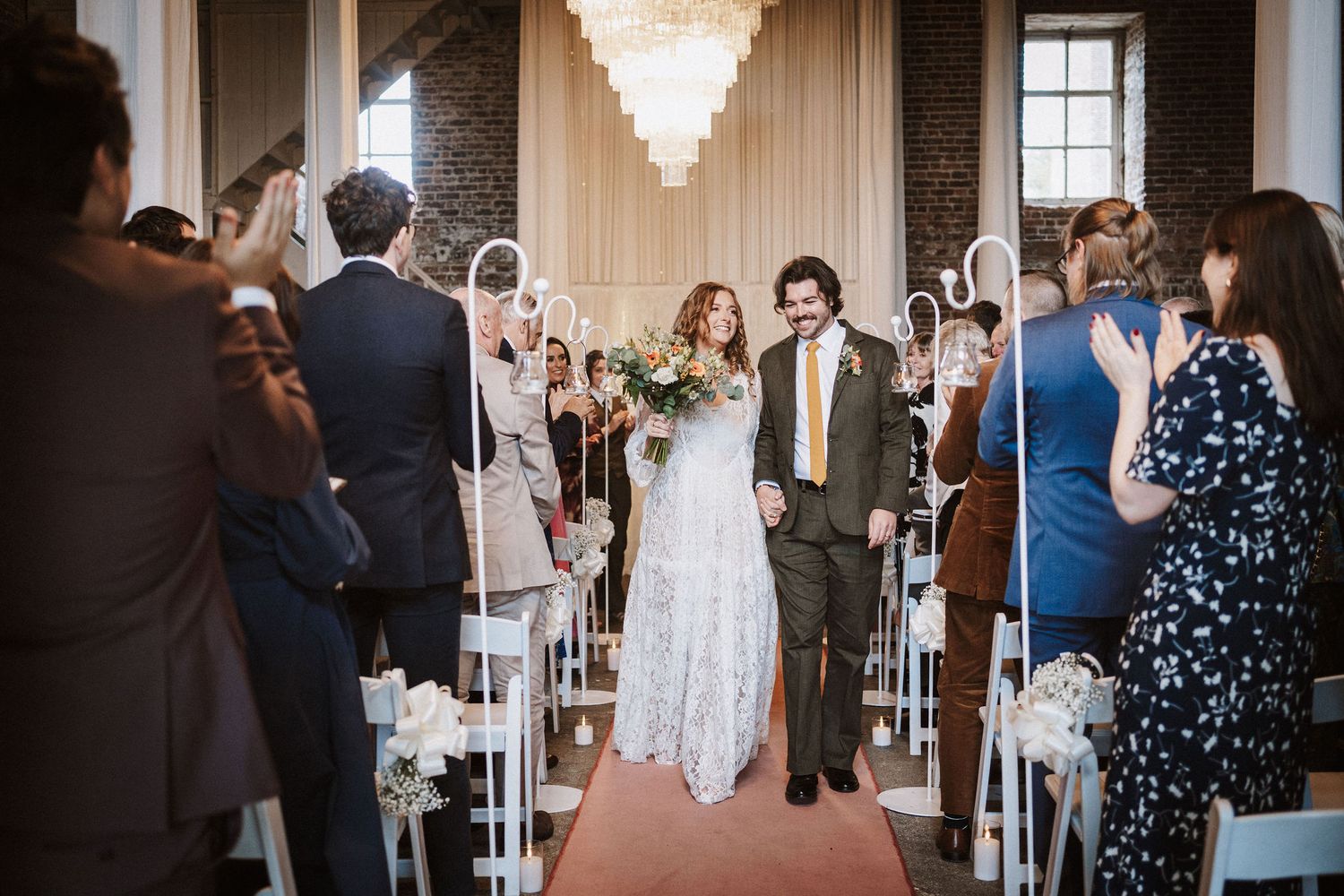 Wedding guests gather in an elegant ballroom with crystal chandeliers for a joyful celebration.