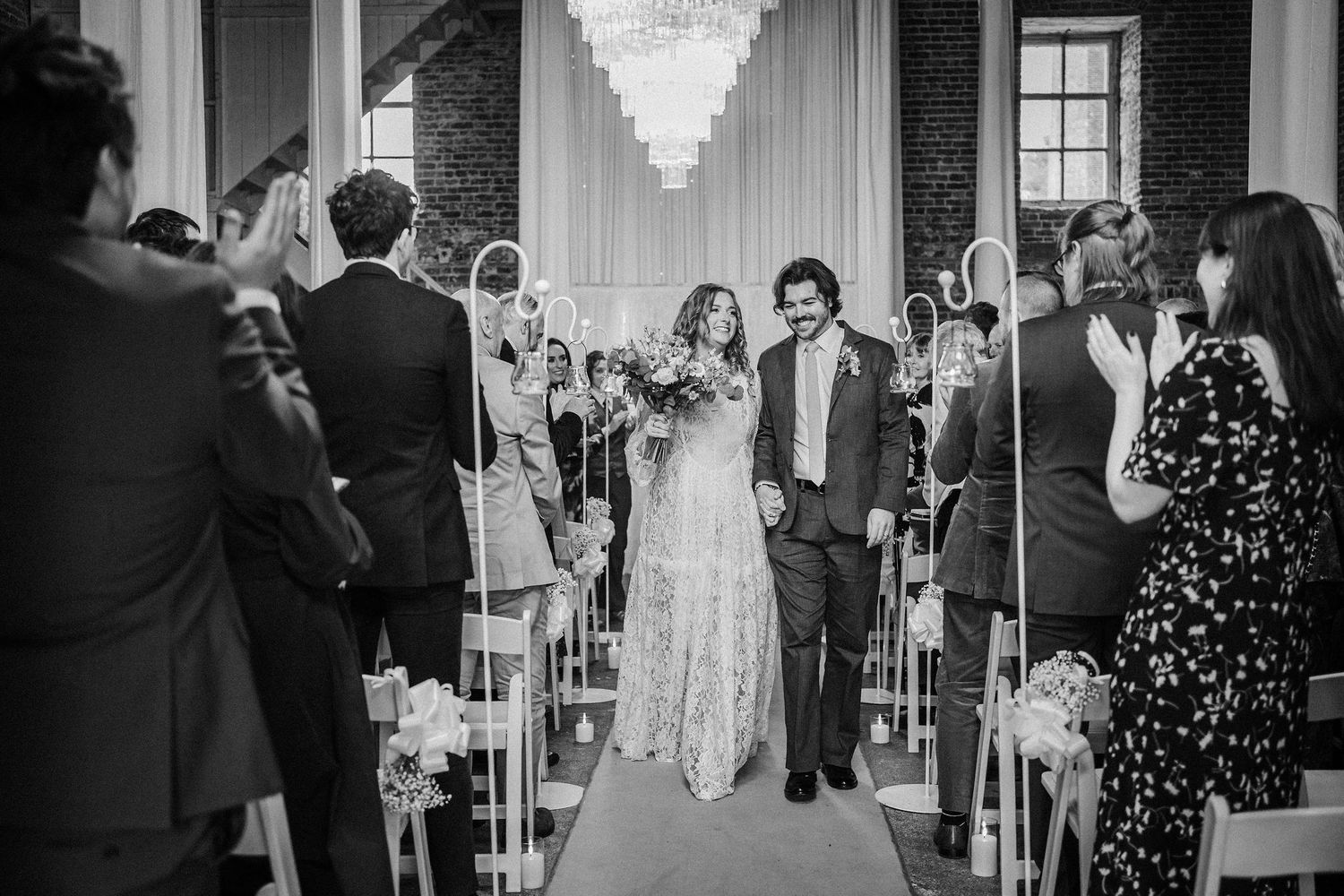 Elegant wedding reception scene with crystal chandeliers and couples dancing in formal attire.