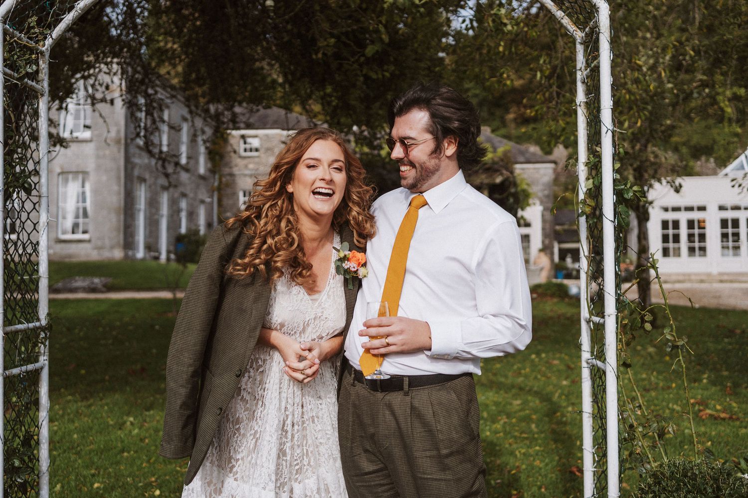 A couple shares a romantic moment together in a garden gazebo surrounded by lush greenery and natural light.