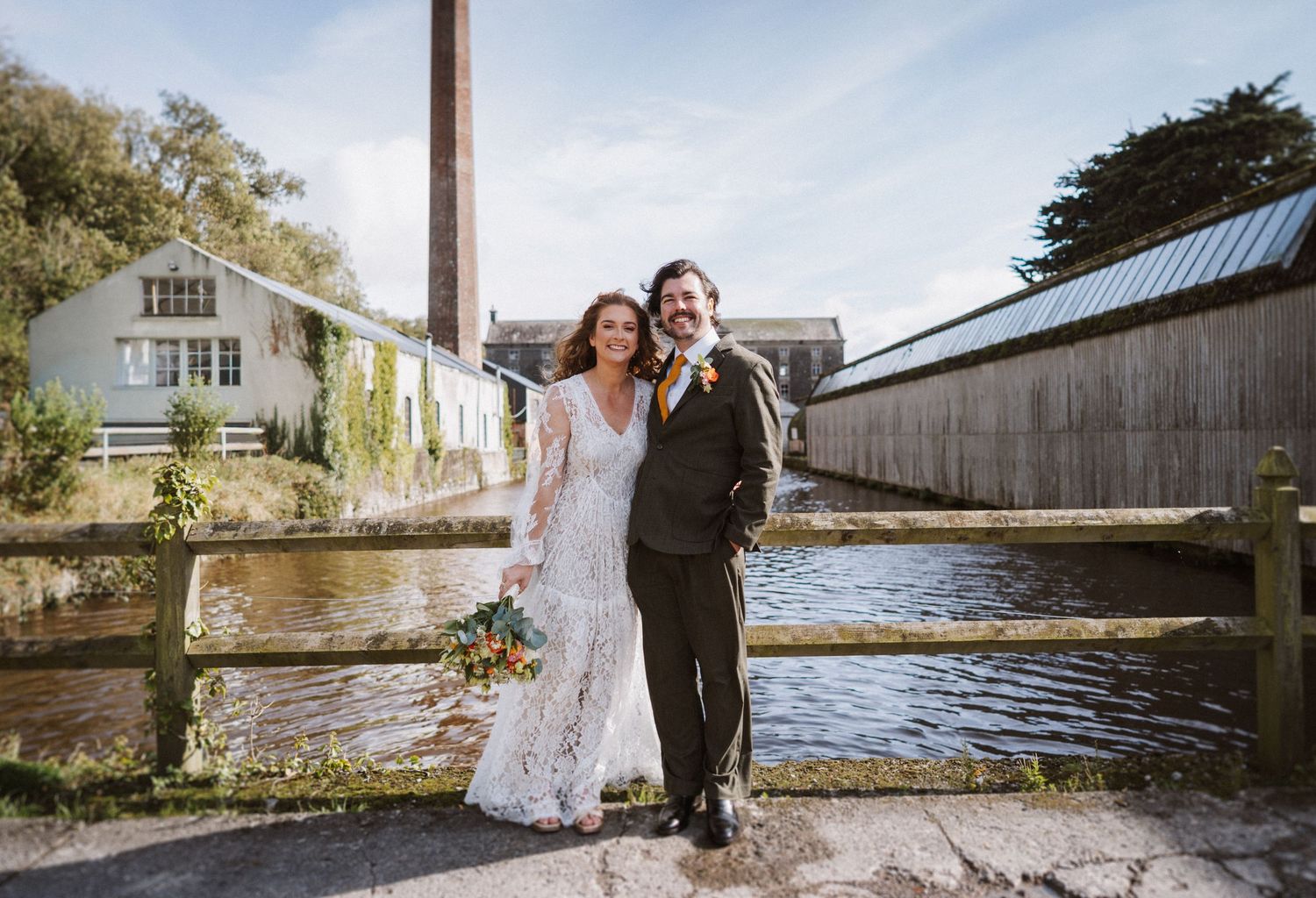 Newlywed couple embraces in front of rustic barn settings during golden hour photoshoot.