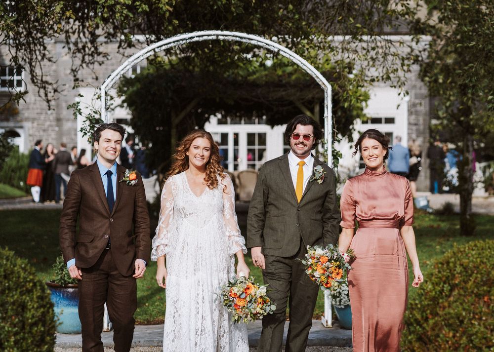 Wedding party members pose outdoors in coordinated brown and peach attire on a sunny autumn day.