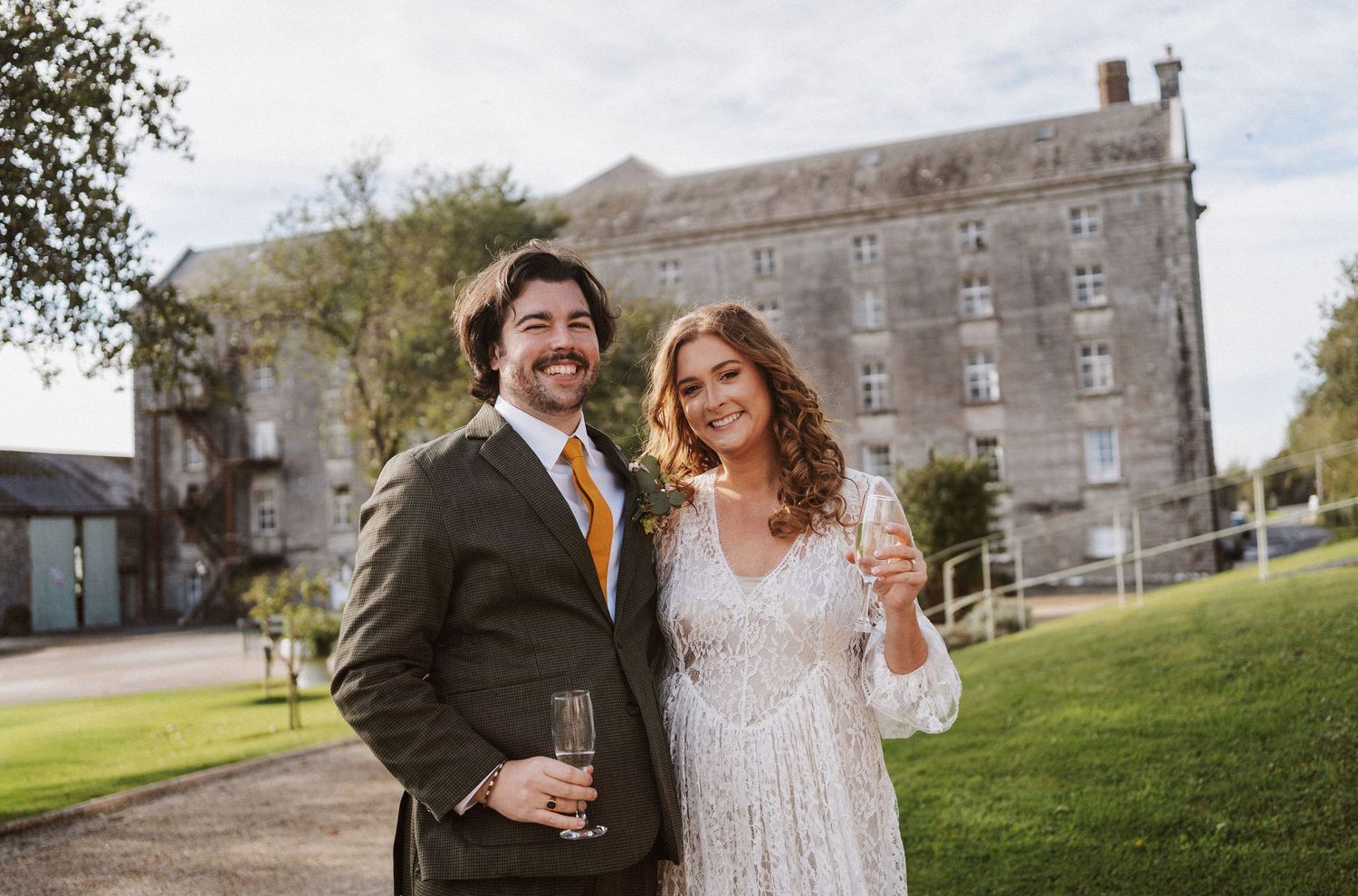 A joyful couple shares a laugh together on their wedding day at a rustic stone building venue.