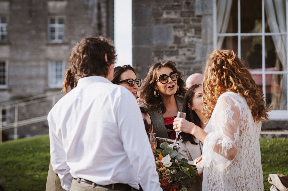Wedding party members laugh and celebrate together during an outdoor summer reception.