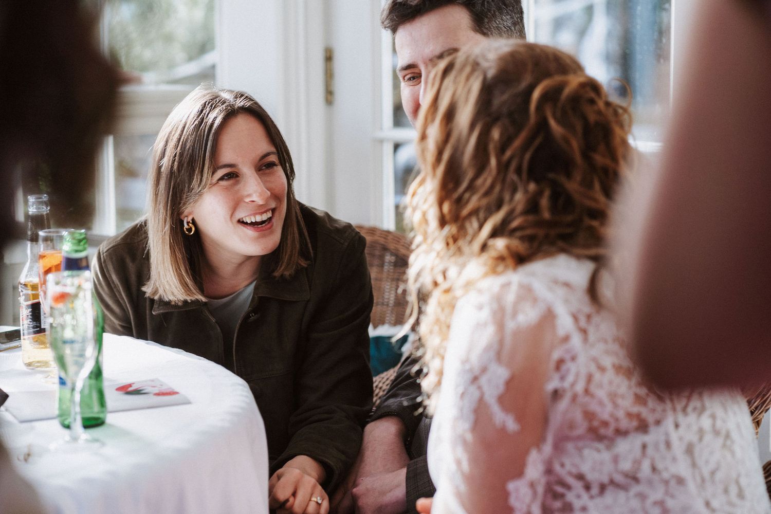Wedding guests share joyful moments during an indoor reception celebration at a dining table.