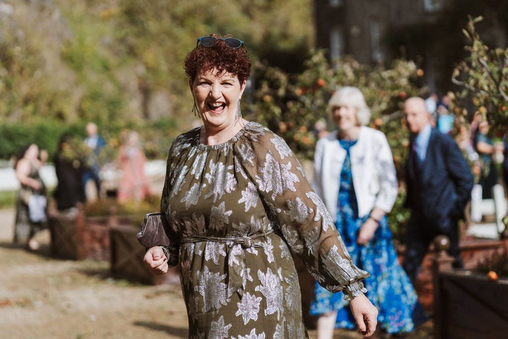 A joyful outdoor wedding celebration with guests gathered in a natural setting surrounded by trees and sunlight.