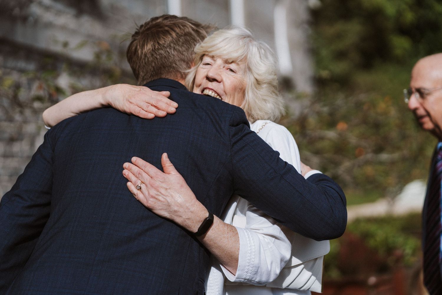 A couple embraces in an intimate moment during their wedding celebration outdoors.