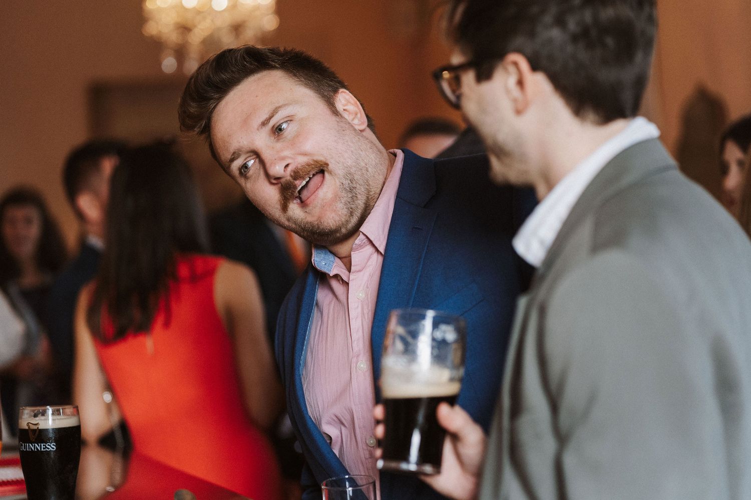 A group of people socializing and laughing together at an indoor networking event with drinks.